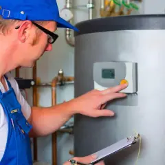 Instalator sprawdza panel sterowania kotła, notując na bieżąco ile kosztuje podłączenie pieca centralnego ogrzewania.