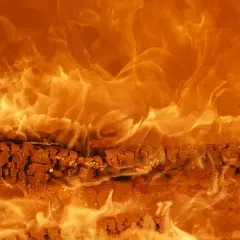 Płonące drewno w kominku, a w tle wirujące płomienie. Czy będzie zakaz palenia pelletem?