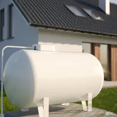 Biały zbiornik na gaz przed nowoczesnym domem.