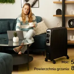 Kobieta z laptopem i kawą obok grzejnika olejowego. Sprawdź, ile prądu bierze grzejnik olejowy o mocy 5700W, ogrzewający 80 m².