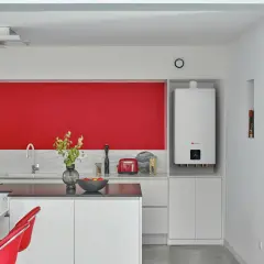 Nowoczesna kuchnia z czerwonym akcentem. Biały bojler wiszący na ścianie, idealne miejsce do montażu czujnika temperatury w bojlerze.