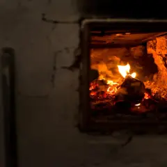 Płonące drewno w palenisku pieca na ekogroszek.
