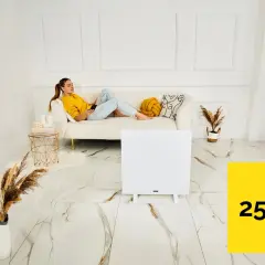 Kobieta relaksuje się na kanapie, podczas gdy grzejnik na podczerwień ogrzewa pomieszczenie o powierzchni 25 m².