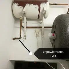 Instrukcja jak odpowietrzyć bojler przy piecu. Strzałka wskazuje zapowietrzoną rurę przy bojlerze.
