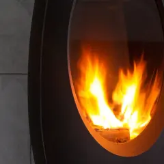 Płonące polana w nowoczesnej kozie, pokazujące, jak palić pelletem w kozie. Ciepło i przytulność.