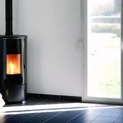 Nowoczesny piec na pellet z palącym się ogniem. Obok stoi worek z pelletem. Zastanawiasz się, czy wyłączać piec na pellet na noc?