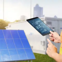 Technik z tabletem analizuje dane z paneli słonecznych. Pokazuje, jak połączyć falownik z wifi, by monitorować energię.