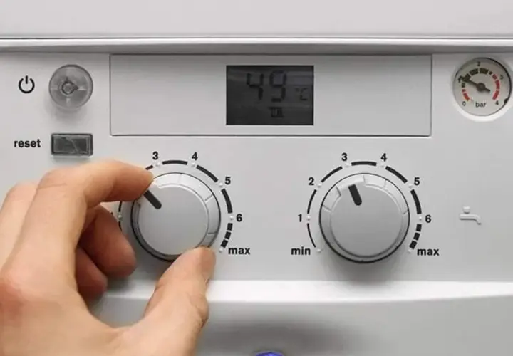 Ręka ustawia pokrętło pieca gazowego dwufunkcyjnego De Dietrich. Cyfrowy wyświetlacz pokazuje 49°C.