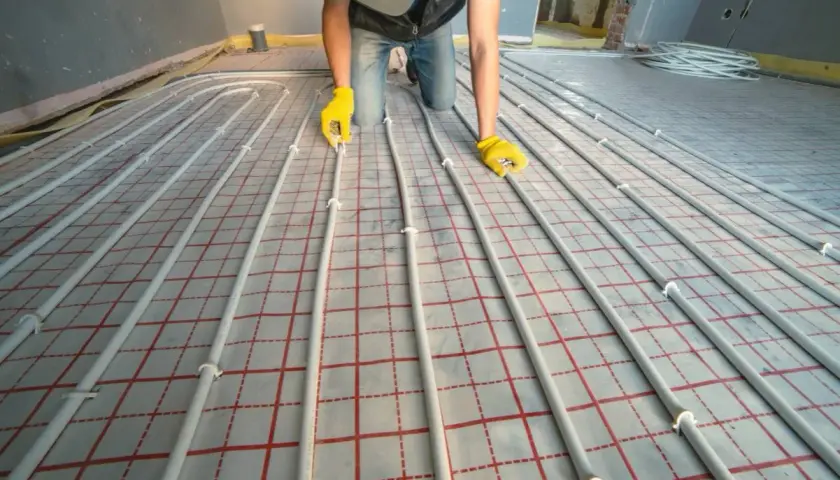 Instalator układa rury do ogrzewania podłogowego. Dokładna ilość metrów rury na m2 podłogówki zależy od projektu.
