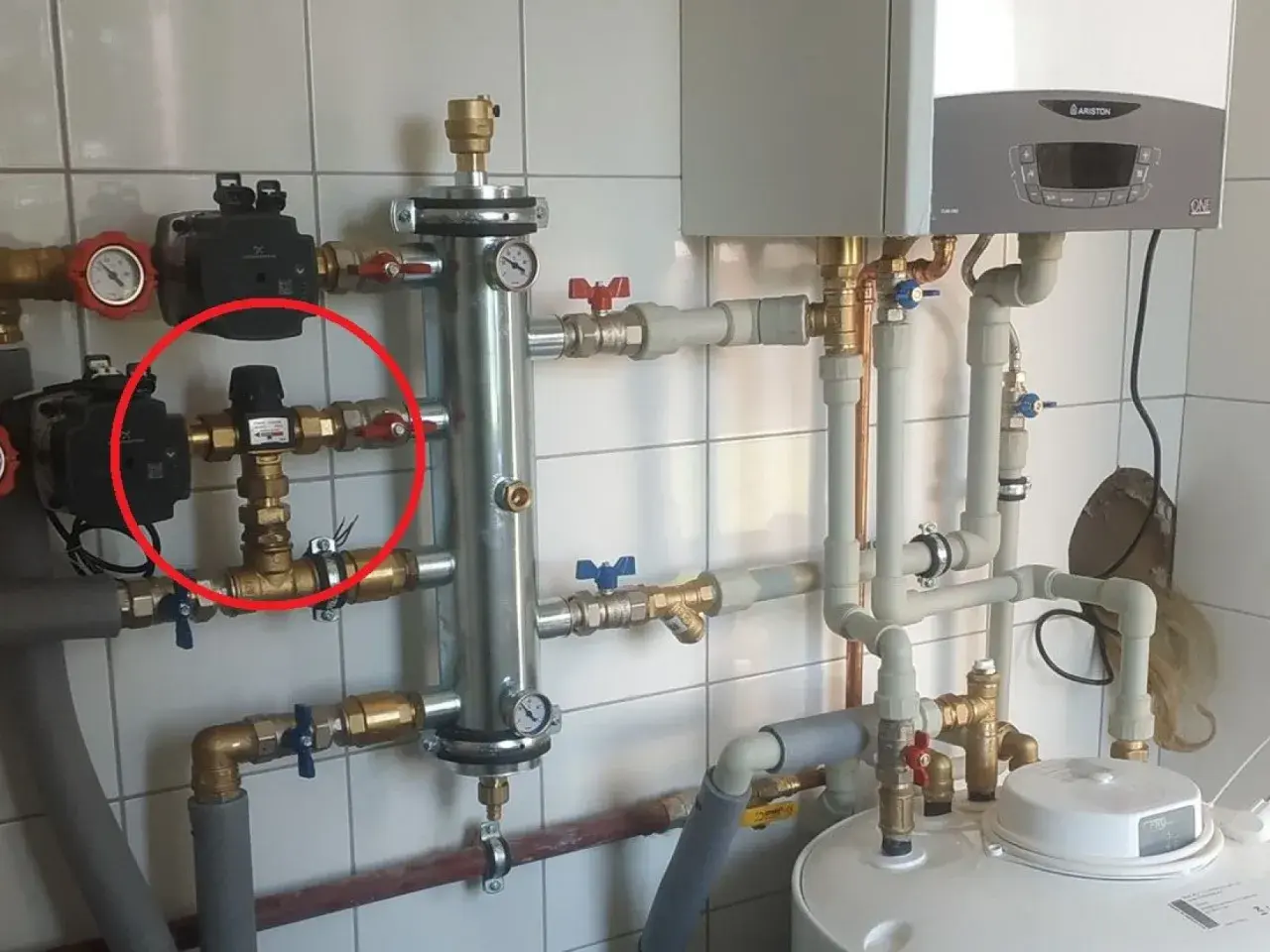 Czerwone kółko zaznacza zawór termostatyczny, kluczowy element systemu grzewczego, który reguluje temperaturę.