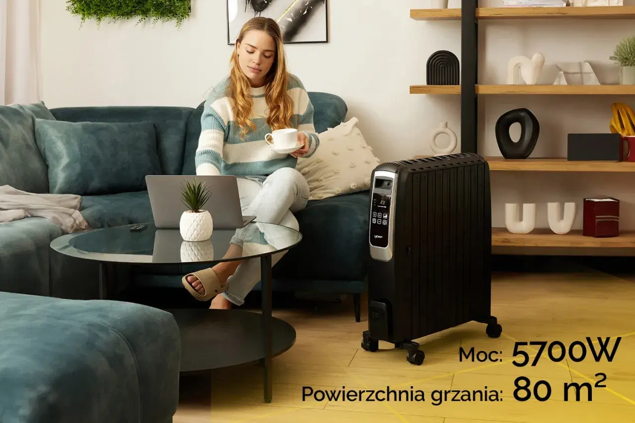Kobieta z laptopem i kawą obok grzejnika olejowego. Sprawdź, ile prądu bierze grzejnik olejowy o mocy 5700W, ogrzewający 80 m².