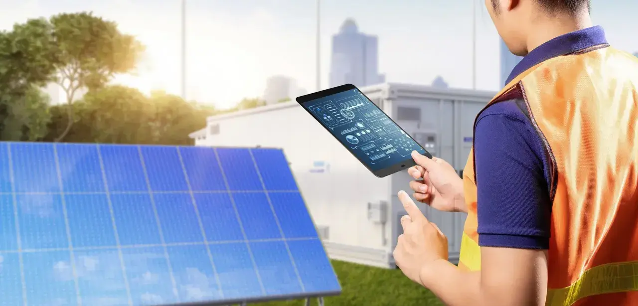 Technik z tabletem analizuje dane z paneli słonecznych. Pokazuje, jak połączyć falownik z wifi, by monitorować energię.