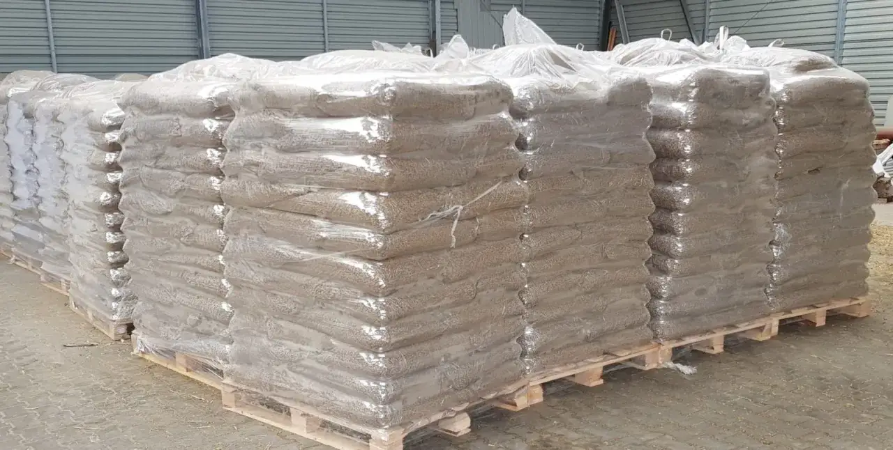 Stosy worków z pelletem na paletach, każdy worek waży ok. 15 kg.